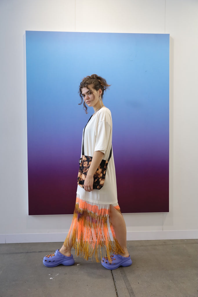 model wearing oversized  shirt with multicolor fringes on the bottom and cross body bag