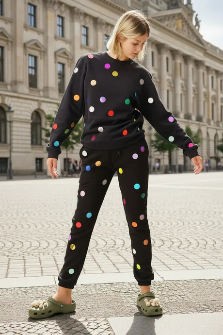 Woman wearing black polka dot sweater and joggers set, outdoors in city plaza