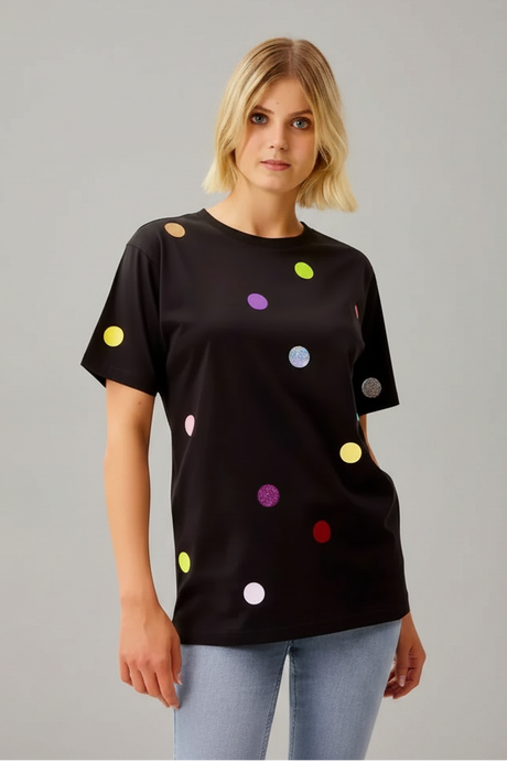 Woman wearing a black t-shirt with colorful polka dots in a bathroom setting