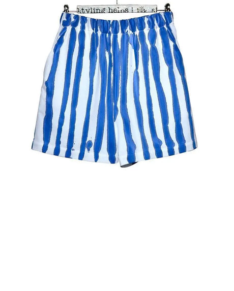 White shorts with bold blue vertical hand-painted stripes, elastic waist, modern design