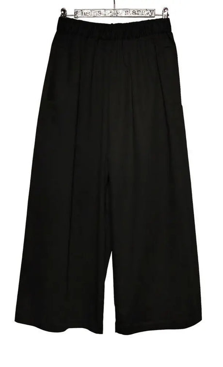 Wide-leg black culotte pants with elastic waistband, hanging against a white background
