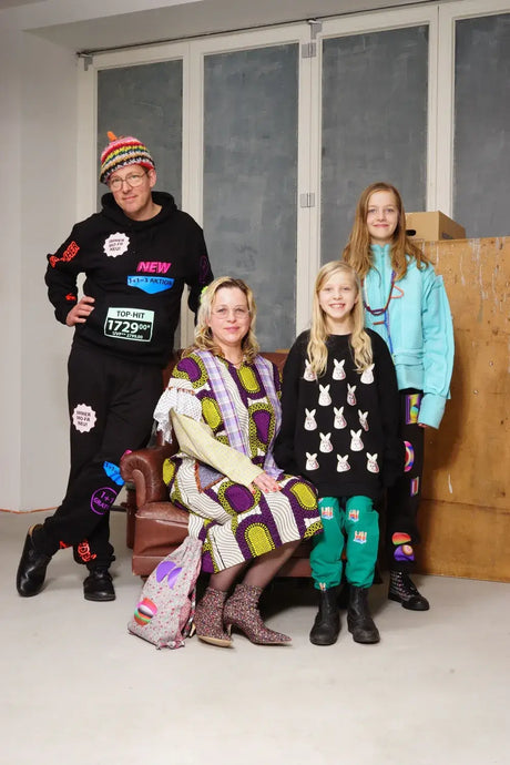Four people wearing colorful, patterned streetwear hoodies and sweaters in a light room