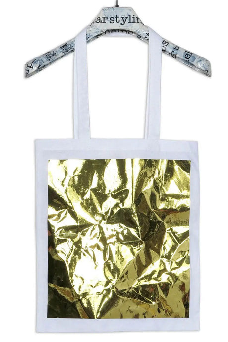 White tote bag with metallic gold foil square design, displayed on a hanger