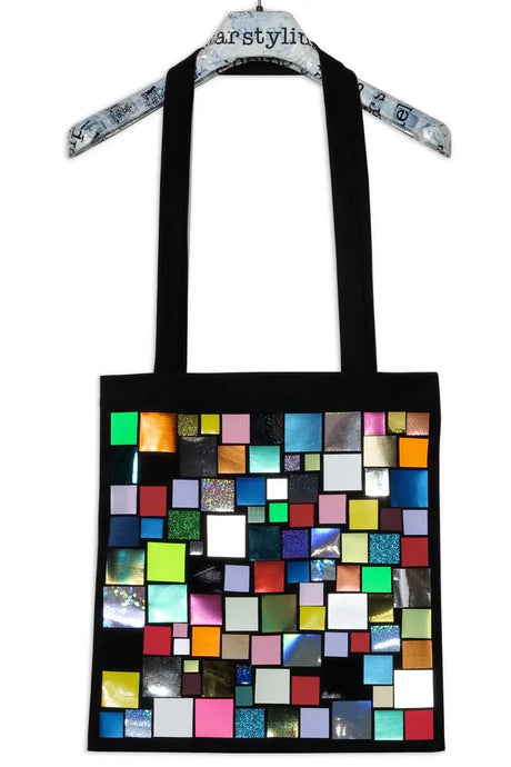 Black tote bag with colorful mosaic square patches, hanging on a graphic hanger