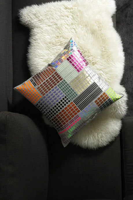 Colorful geometric pattern cushion on white faux fur throw and dark sofa