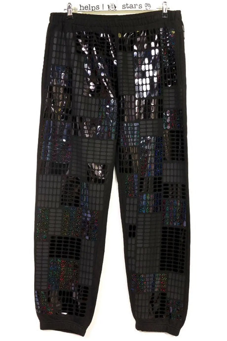 Black jogger pants with grid pattern and iridescent sequin patches hanging on hanger