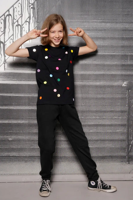Smiling child wearing black t-shirt with colorful polka dots and black pants