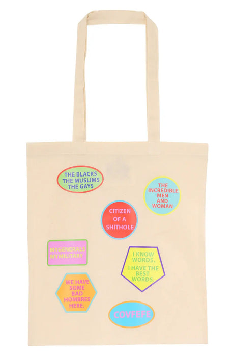 Beige tote bag with colorful patches featuring various satirical phrases and bold text.